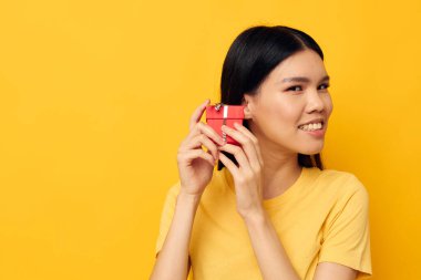 Çekici genç Asyalı kadın elinde hediye kutusuyla stüdyo modelini değiştirmeden poz veriyor.