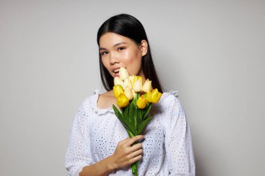 Bir buket çiçekle büyüleyici genç Asyalı kadın. Arka planda hiç değişmeden gülümse.