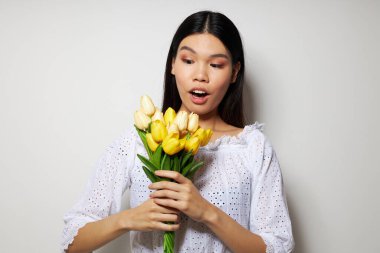 Beyaz gömlekli, Asyalı bir kadın. Çiçekler. Stüdyo modeli gibi poz veriyor.