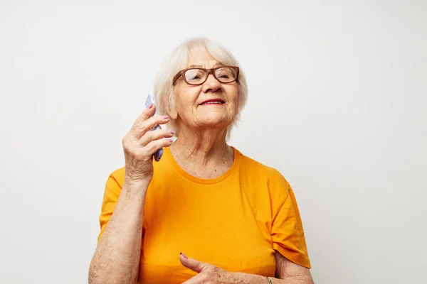 Пожилая женщина в жёлтой футболке, позирующая на фоне телефонного освещения — стоковое фото