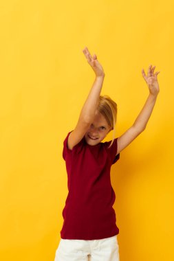 Küçük kız yerde oturmuş günlük kıyafetlerle poz veriyor.