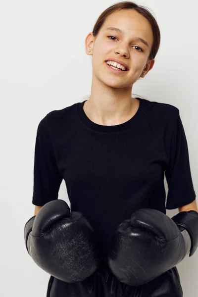 Atletische vrouw in bokshandschoenen in zwarte broek en een T-shirt geïsoleerde achtergrond — Stockfoto