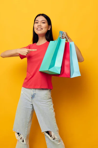 Portret aziatische mooie jonge vrouw shopping tassen in rood t-shirt geïsoleerde achtergrond ongewijzigd — Stockfoto