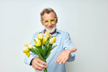 Yaşlı adam sarı çiçek buketi açık arkaplan pozu veriyor.