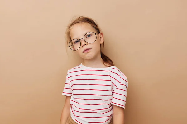 Mignonne petite fille lunettes rondes posant fond beige — Photo