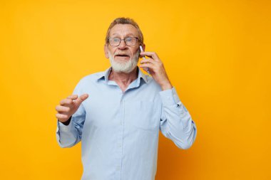 Telefon sapsarı arka planda konuşan gözlüklü yaşlı bir adam portresi.