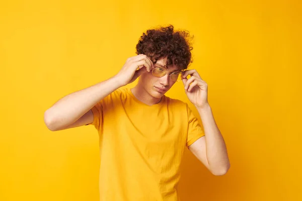 Joven rizado hombre amarillo camiseta gafas moda mano gestos aislado fondo inalterado — Foto de Stock