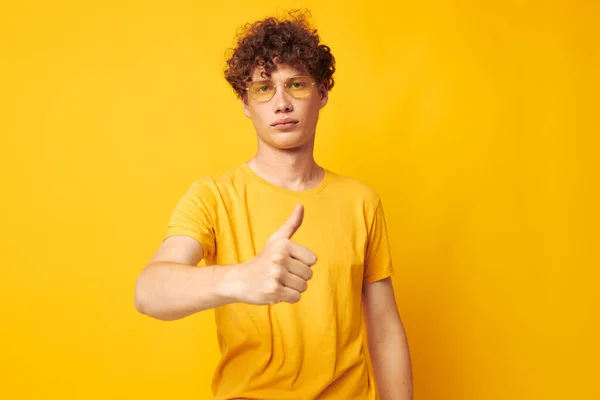 Jeune homme aux cheveux bouclés portant des lunettes élégantes t-shirt jaune posant fond isolé inaltéré — Photo