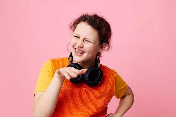 Pretty girl listening to music with headphones orange sweater emotions fun cropped view unaltered — 图库照片