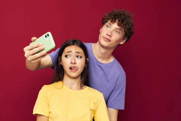 Bel ragazzo e ragazza in t-shirt colorate con un telefono Stile giovanile — Foto Stock