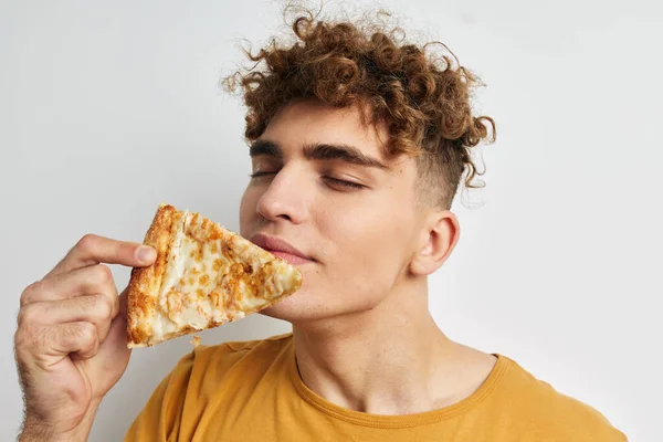 Handsome guy eating pizza posing close-up light background — 图库照片