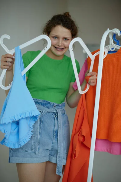 Веселая женщина гладит одежду на вешалке гардероб изолированные фоны без изменений — стоковое фото