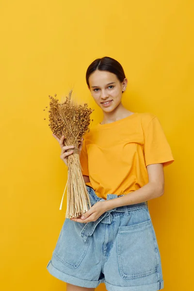 Foto chica bonita moda en amarillo camiseta flores secas ramo posando fondo aislado —  Fotos de Stock