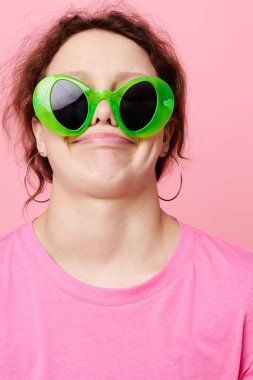 Yeşil gözlüklü, elleri pembe arka planlı genç bir kadın.