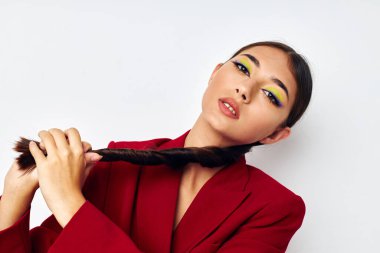 Güzel esmer, parlak makyajlı, kırmızı ceketli, açık arkaplan görünümlü.