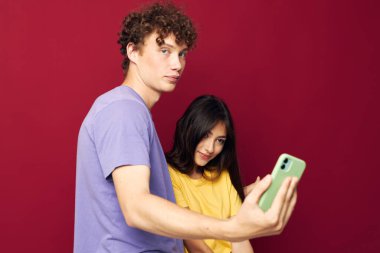 Genç adam ve kız renkli tişörtler içinde telefon kırmızı arkaplan