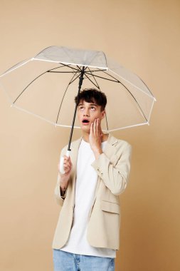 Yağmurdan korunmak için açık şemsiyeli ceketli hoş bir adam.