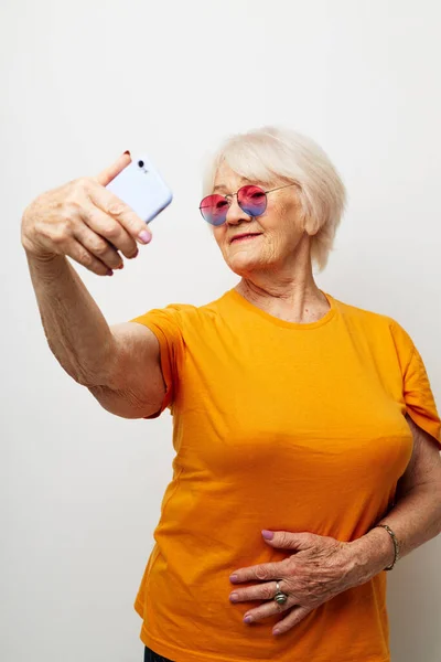 Elderly woman in a yellow t-shirt posing communication by phone close-up emotions — Stock Photo, Image