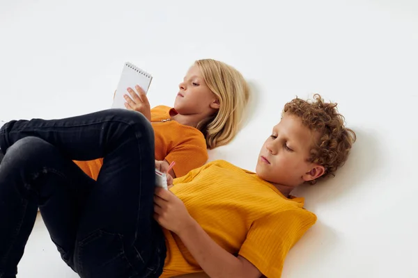 즐거운 아이들 이 노트와 연필로 어린 시절 의생활을 그대로 바꾸어 놓고 바닥에 누워 있다 — 스톡 사진