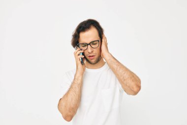 Beyaz tişörtlü yakışıklı adam telefonla iletişim kuruyor.