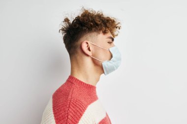 Çizgili kazaklı yakışıklı adam tıbbi maske takıyor.