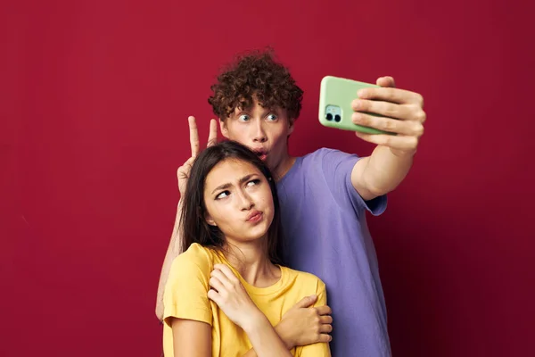 Uomo e donna in T-shirt colorate con uno sfondo isolato telefono — Foto Stock