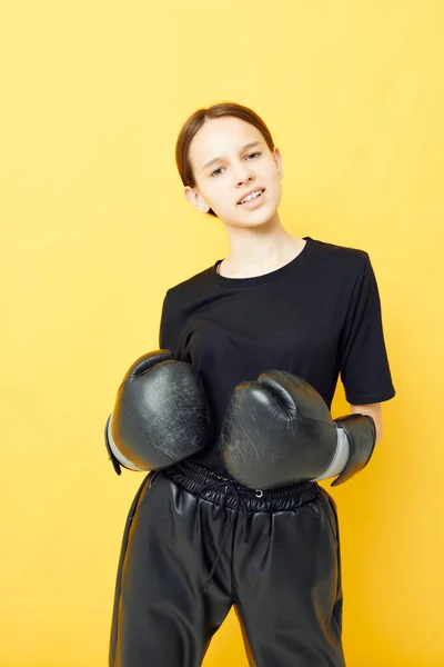 若い女性黒ボクシング手袋ポーズ黄色の背景スポーツ — ストック写真