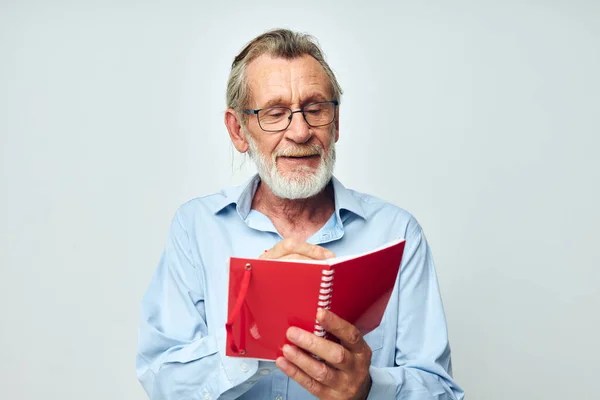 Old man writes down emotions in a notebook light background — Stock fotografie