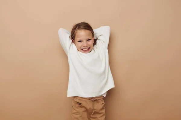 Kleines Mädchen im weißen Pullover posiert Handgesten beigen Hintergrund — Stockfoto