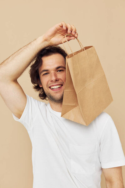 Attractive man in a white T-shirt with paper bag isolated background