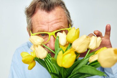Yaşlı adam sarı çiçek buketi açık arkaplan pozu veriyor.