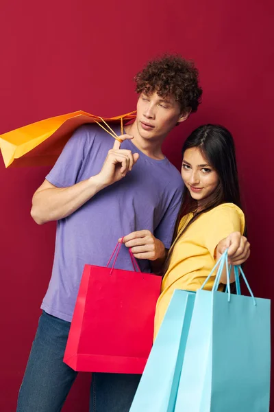 Портрет чоловіка і жінки в барвистих футболках з сумками Шопінг червоний фон незмінний — стокове фото