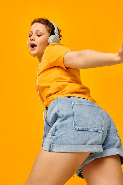 Jolie fille portant des écouteurs jeans shorts close-up émotions Lifestyle inchangé — Photo