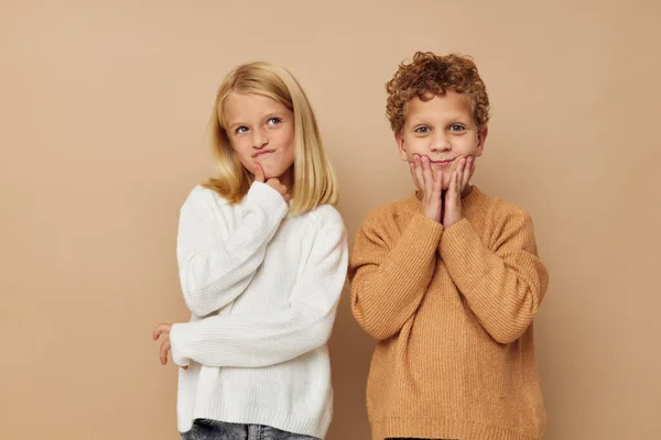 Boy and girl standing next to posing emotions beige background — Φωτογραφία Αρχείου