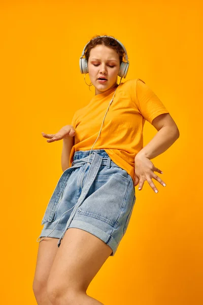 Mooie vrouw geel t-shirt hoofdtelefoon entertainment muziek leuk geïsoleerde achtergronden ongewijzigd — Stockfoto