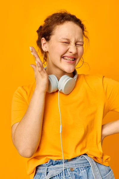 Güzel kadın kulaklıkları buruşturdu müzik teknolojisi sarı arka plan değiştirilmedi — Stok fotoğraf