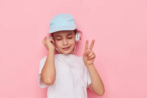 Χαριτωμένο κορίτσι ακουστικά σε ένα λευκό t-shirt και ένα καπάκι Lifestyle αμετάβλητη — Φωτογραφία Αρχείου