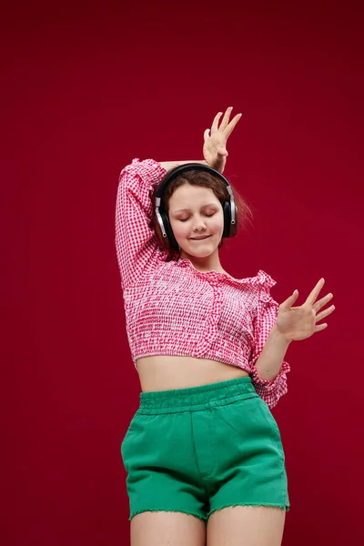 Mulher alegre em shorts verdes ouvindo música em fones de ouvido — Fotografia de Stock