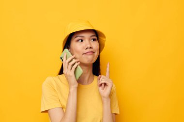 Güzel esmer, telefonda konuşuyor. Moda modasına uygun, değiştirilmemiş bir arka plan.