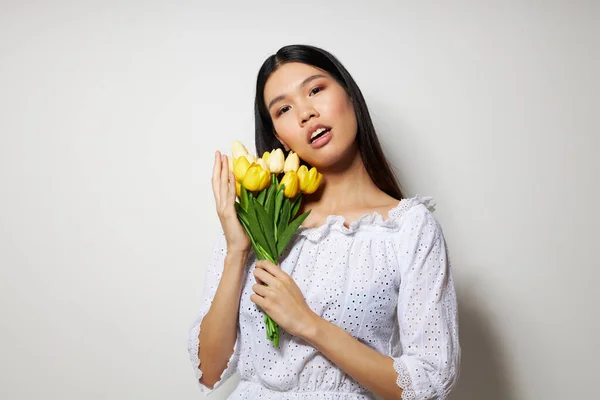 Woman with Asian appearance romance bouquet of flowers near the face studio model unaltered — Stock fotografie