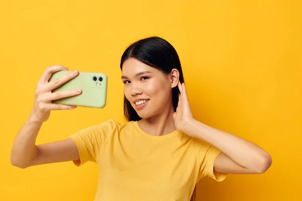 Mulher com um smartphone em mãos emoções divertidas close-up fundo amarelo inalterado — Fotografia de Stock