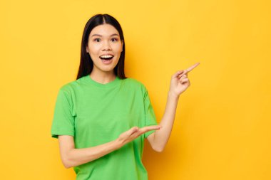 Asyalı kadın yeşil t-shirt pozu veriyor. Duygular, fotokopi alanı izole edilmiş arka plan değiştirilmemiş.