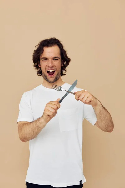 Vrolijke man in een wit T-shirt met mes met vork Lifestyle ongewijzigd — Stockfoto