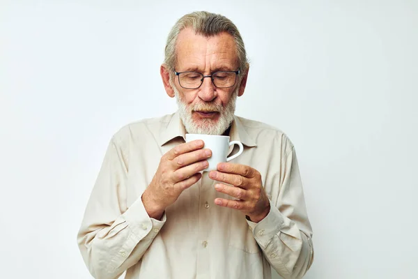 Starší muž drží hrnek na bílém pozadí — Stock fotografie