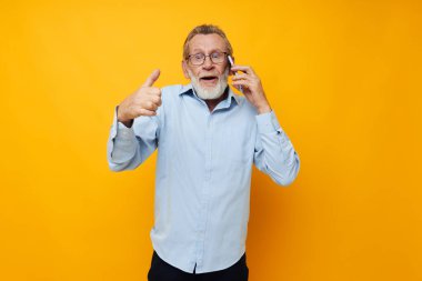 Yaşlı gri saçlı adam telefonda konuşuyor. Yakın çekim görüntüsü veriyor.
