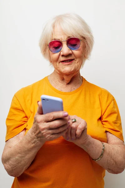 스마트폰을 손에 쥔 최신 안경을 쓴 노부인 — 스톡 사진