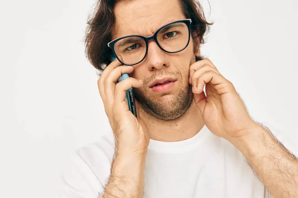 Hombre guapo en una comunicación camiseta blanca por fondo de luz del teléfono — Foto de Stock