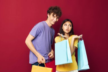 Renkli çantalarla alışveriş yapan bir erkek ve kadının portresi değiştirilmemiş bir arka plan.