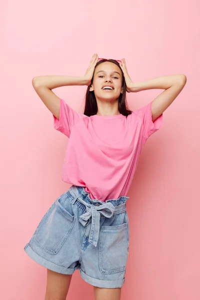 Ung vacker kvinna i en rosa t-shirt casual kläder rosa bakgrund — Stockfoto