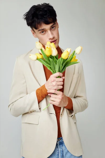 写真若いボーイフレンドで白いジャケットで花束の黄色の花エレガントなスタイルライフスタイル変更されない — ストック写真